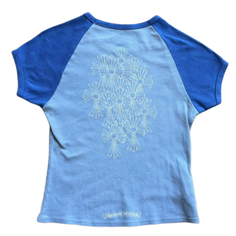 Back flat lay view of the two-tone blue vintage Chrome Hearts baby tee, highlighting the cropped streetwear proportions and sporty raglan sleeve seams across the upper shoulders, dominated by a large, central tonal graphic screen-printed across the back torso depicting an intricate gothic cemetery cross cluster arrangement.