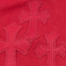 A close-up layout shot focusing on the upper front thigh area, highlighting the rich, premium grain texture of multiple cherry-red leather signature cemetery cross patches meticulously hand-stitched onto the matching red denim background canvas.