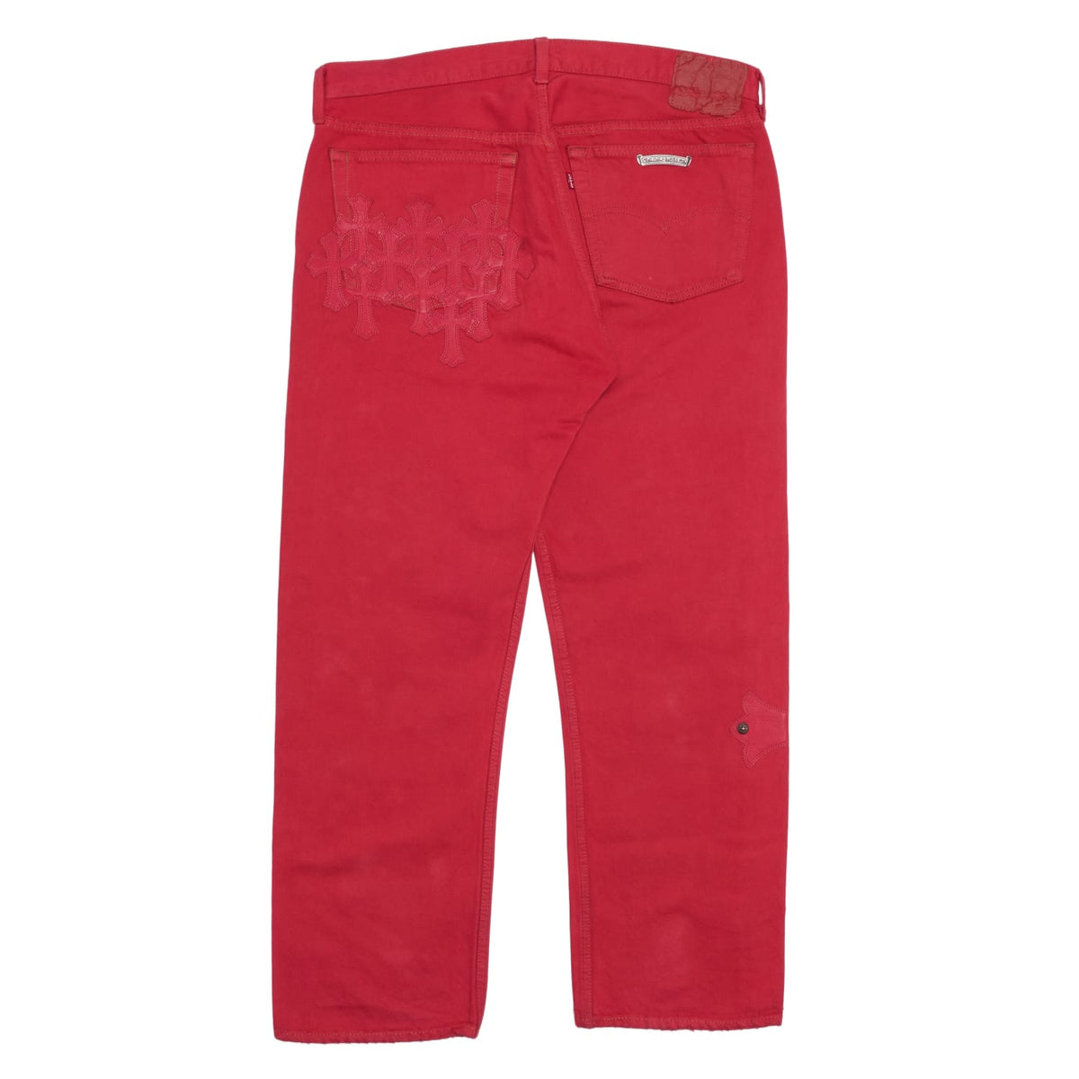 Back flat lay view of the cherry-red Chrome Hearts dyed jeans, highlighting the tailored straight-cut silhouette stretching down from the waistband to the straight lower hems, featuring a clean rear profile accented by tonal red leather cross patches layered across the back pockets and seat.