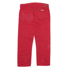 Back flat lay view of the cherry-red Chrome Hearts dyed jeans, highlighting the tailored straight-cut silhouette stretching down from the waistband to the straight lower hems, featuring a clean rear profile accented by tonal red leather cross patches layered across the back pockets and seat.