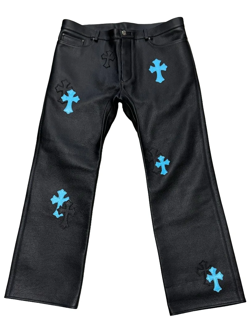 Front flat lay view of the Chrome Hearts custom leather pants in black full-grain leather, featuring a straight-leg silhouette and multiple stacked, hand-stitched signature cross patches in contrasting electric blue leather scattered across the front legs.