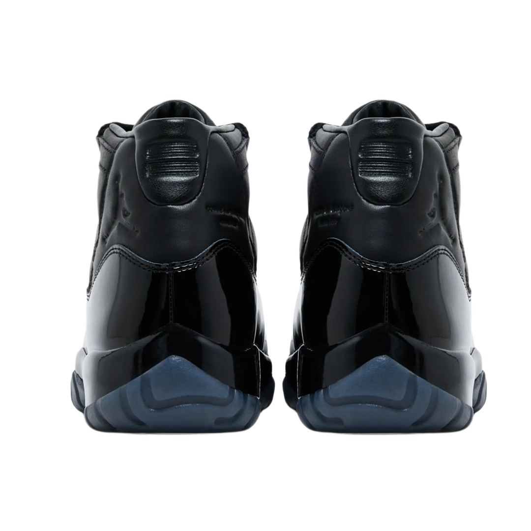 A back-facing view of both Jordan 11 x Comme des Garçons sneakers, showcasing the premium black full-grain leather heels with debossed tonal Jumpman logos, stylized '23' branding on the collar tabs, and deep smoky blue translucent outsole pods.