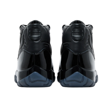 A back-facing view of both Jordan 11 x Comme des Garçons sneakers, showcasing the premium black full-grain leather heels with debossed tonal Jumpman logos, stylized '23' branding on the collar tabs, and deep smoky blue translucent outsole pods.