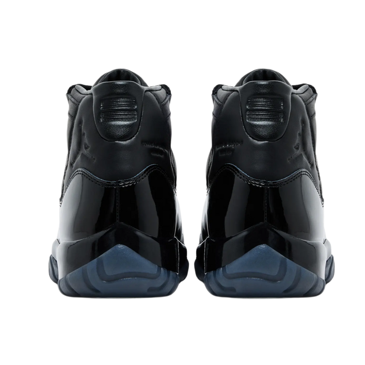 A back-facing view of both Jordan 11 x Comme des Garçons sneakers, showcasing the premium black full-grain leather heels with debossed tonal Jumpman logos, stylized '23' branding on the collar tabs, and deep smoky blue translucent outsole pods.
