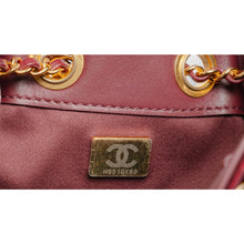 A detailed close-up shot focusing on the lower corner seam layout, showcasing the structural integrity of the curved piping borders, the high-gloss patina of the burgundy leather under studio lighting, and a glimpse of the gold chain anchor points.