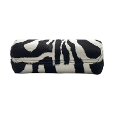 An angled side-profile view of the closed 'Green Zebra' leather watch roll resting horizontally, showcasing the continuous flow of the vibrant neon green and black zebra pattern across the curved leather paneling, immaculate black perimeter edge glazing, and tight structural stitching.