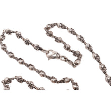 Close-up view of the substantial sterling silver necklace chain loosely coiled, emphasizing the high-polish finish, micro-engraved link connectors, and secure lobster clasp enclosure.