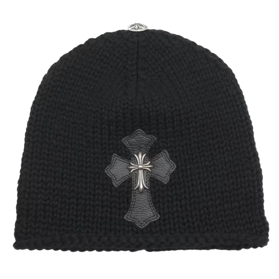 Front flat lay view of the Chrome Hearts beanie in a premium black cashmere knit, featuring a thick textured weave structure embellished with a large black leather cross patch centered on the front cuff and overlaid with a heavy sterling silver floral cross hardware centerpiece.