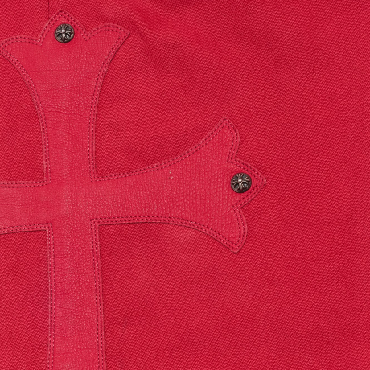 A close-up view focusing on the front right hip panel, highlighting the heavy twill weave texture of the red dyed denim canvas, precise tonal stitching along the traditional curved side slip pocket, and clean seam joins framing the upper waistband area.