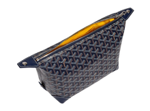 An elevated view looking down into the open Goyard toiletry bag, showcasing the spacious main compartment lined with signature vibrant yellow canvas fabric and detailed with a clean leather trim lining the top zipper path.