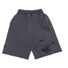 Back flat lay view of the faded dark grey Paly sweat shorts, showcasing a relaxed silhouette with an unadorned seat and subtle black distressed graphic prints accenting the outer lower legs near the raw hems.