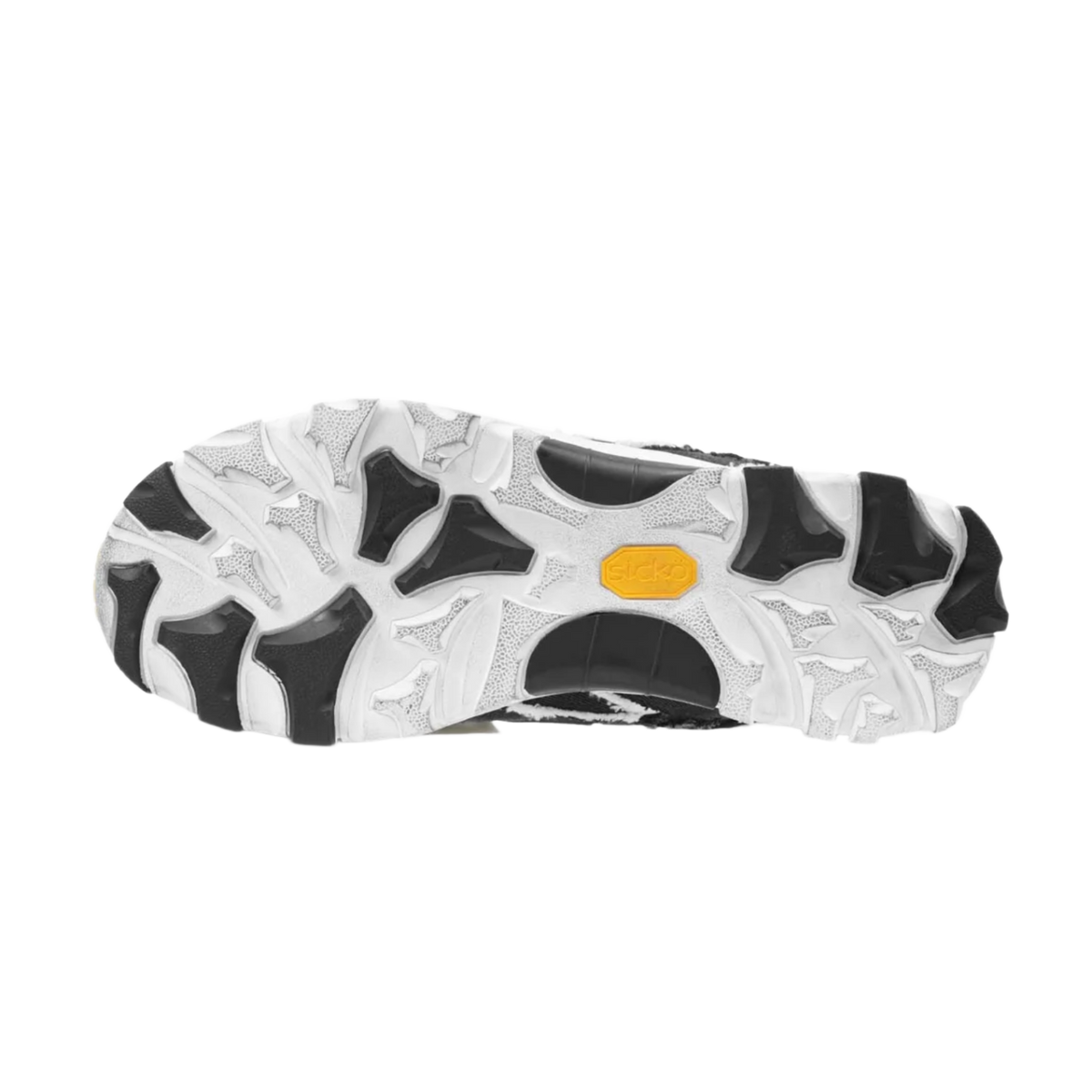 A full view of the underside of the shoe, showcasing the heavy-duty high-traction rubber outsole layout featuring an aggressive, organic multi-directional lug design executed in a striking marbled white-and-black camo pattern, split by a solid black structural midfoot shank plate for technical trail stability.