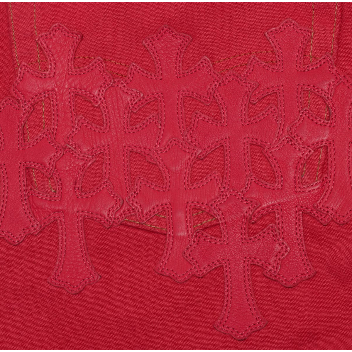 A detailed close-up shot focusing across the upper rear seat and pockets, showcasing a dense, multi-layered cluster of tonal red leather cross patches hand-stitched symmetrically across the back denim panels.