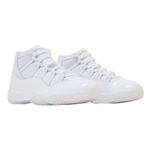 A pair of monochrome triple-white Comme des Garçons x Air Jordan 11 sneakers shown at a three-quarter angle, highlighting the premium matte white leather upper, pristine white patent leather mudguard, and solid white rubber outsole.