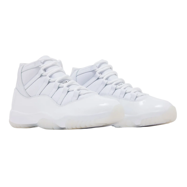 A pair of monochrome triple-white Comme des Garçons x Air Jordan 11 sneakers shown at a three-quarter angle, highlighting the premium matte white leather upper, pristine white patent leather mudguard, and solid white rubber outsole.