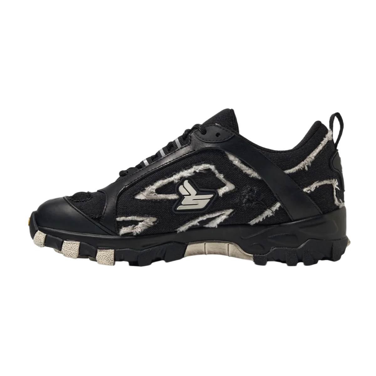 A lateral side profile view of the Sicko Vessel hiking shoe, showcasing a technical low-top trail silhouette with a black breathable mesh upper enveloped in a jagged, multi-layered black nubuck and leather cage overlay, detailed with a white embroidered stylized 'S' graphic emblem on the side panel, patterned hiking laces, a canvas heel pull tab, and a chunky, high-traction black rubber midsole.