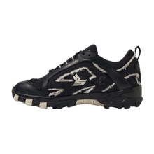 A lateral side profile view of the Sicko Vessel hiking shoe, showcasing a technical low-top trail silhouette with a black breathable mesh upper enveloped in a jagged, multi-layered black nubuck and leather cage overlay, detailed with a white embroidered stylized 'S' graphic emblem on the side panel, patterned hiking laces, a canvas heel pull tab, and a chunky, high-traction black rubber midsole.